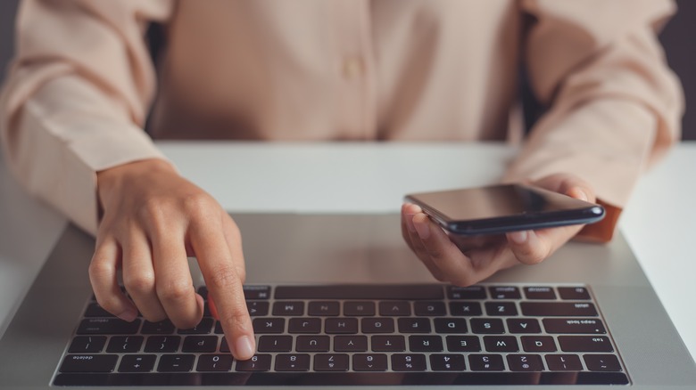 Someone using a laptop and phone