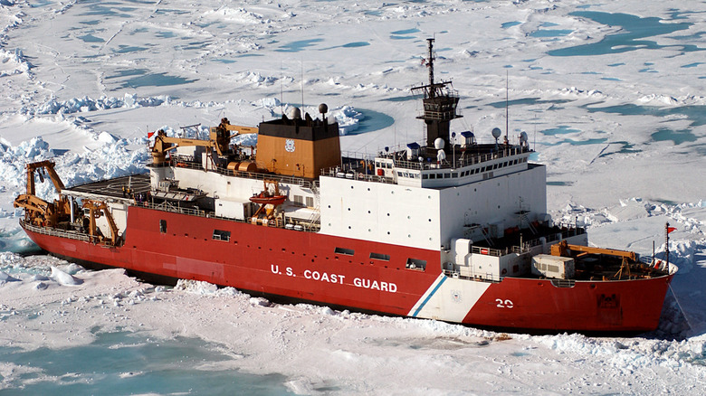 A large red and white ship in frozen seas, surrounded by ice.