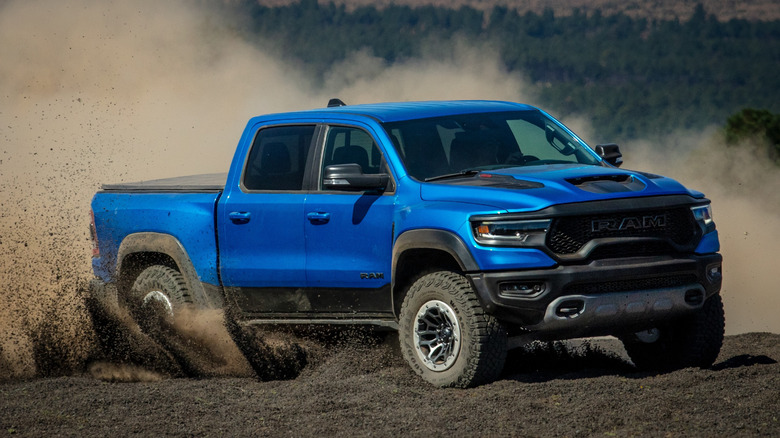 2024 RAM TRX with 6.2L supercharged Hemi V8 off-roading in black sand, front-right view