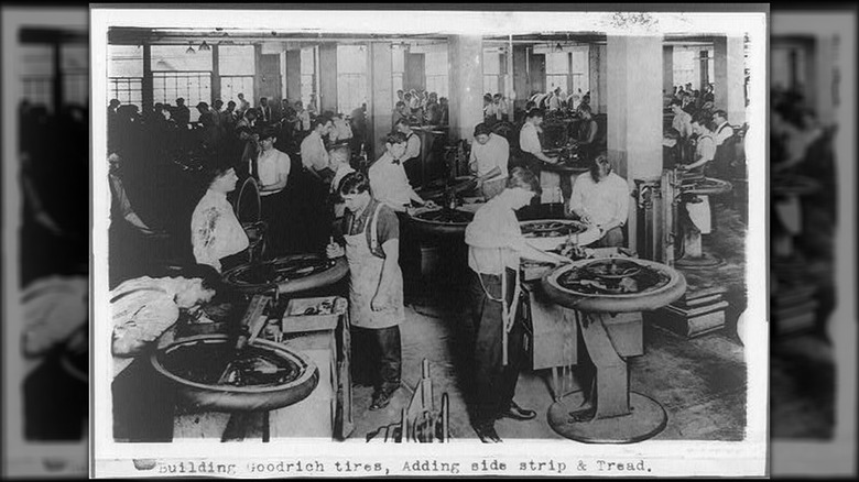 Workers building Goodrich tires, adding side strip and treads.