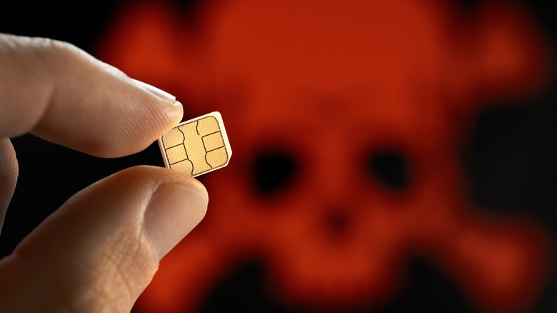 Close-up of a SIM card in front of a red skull and crossbones
