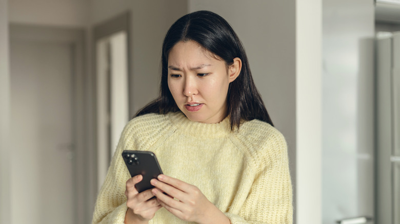 Young woman looking at her cell phone with a concerned expression