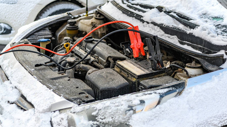 Car covered in snow being jump started in the cold