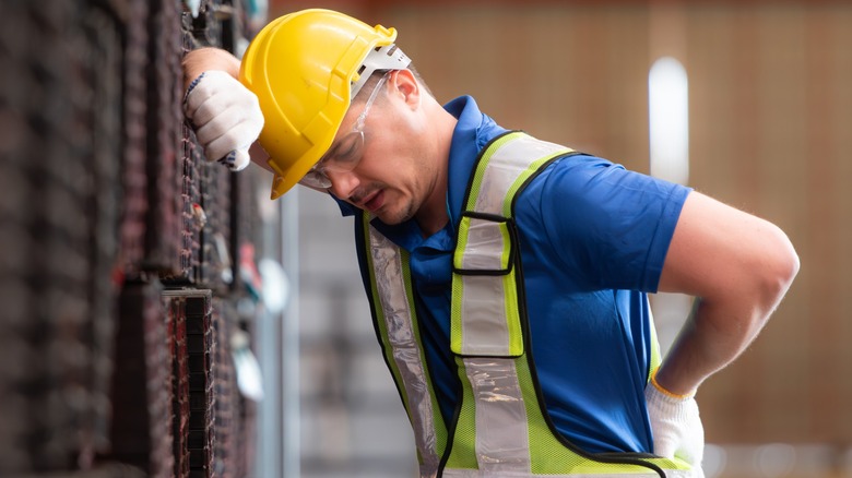 Worker in hardhat struggling with back pain
