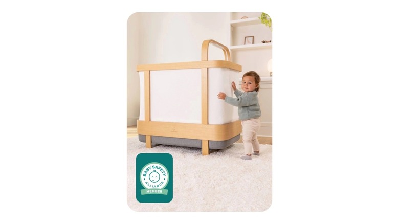 A baby hugging a Cradlewise smart bassinet and crib
