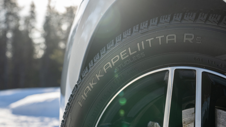 Sidewall of Nokian Tyres Hakkapeliitta R5 on front of car in wooded setting