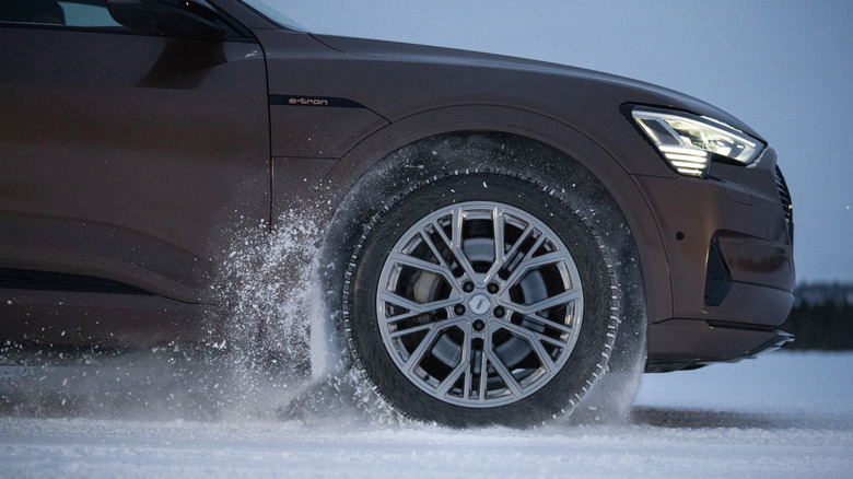 Closeup side view of Audi e-tron driving through snowy conditions