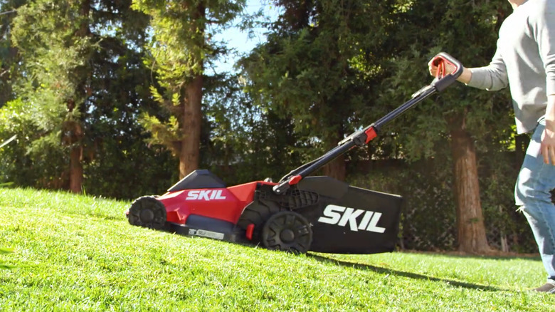Man pushing Skil PM4910-10 in an inclined yard
