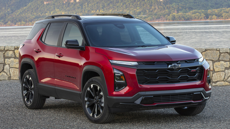 Red Chevrolet Equinox parked in front of a stone wall next to a lake