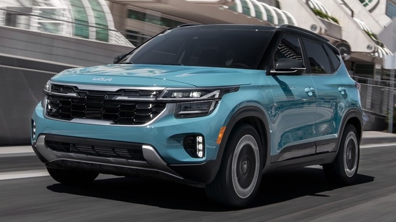 Teal Kia Seltos driving on an urban road