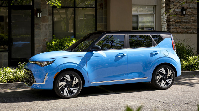Blue Kia Soul parked on a leafy urban street