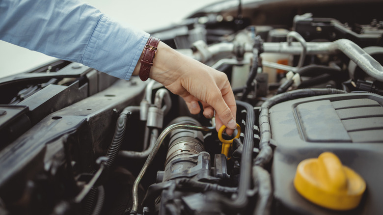 A person using a dipstick to check the oil in their car