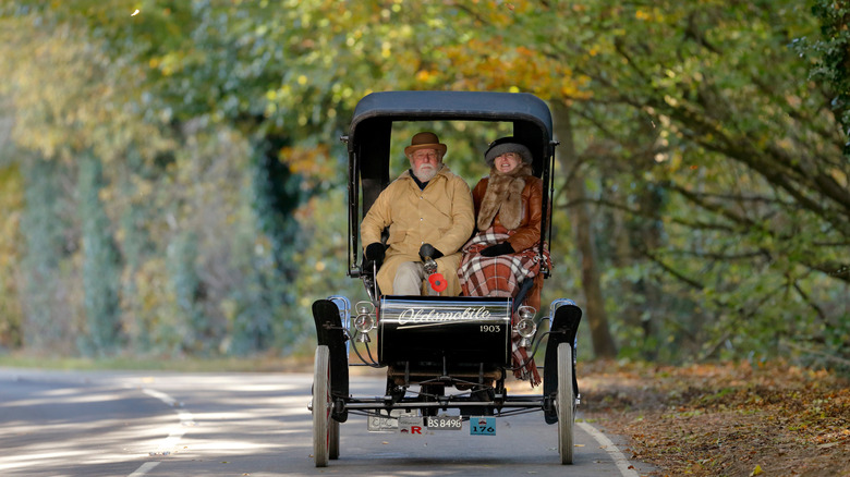 Front shot of a 1903 Oldsmobile driving on a scenic road