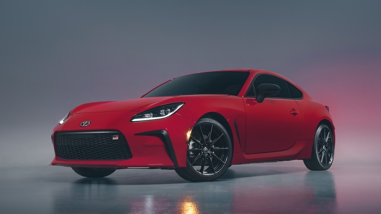 Front 3/4 shot of a red 2022 Toyota GR86 in studio with moody lighting.