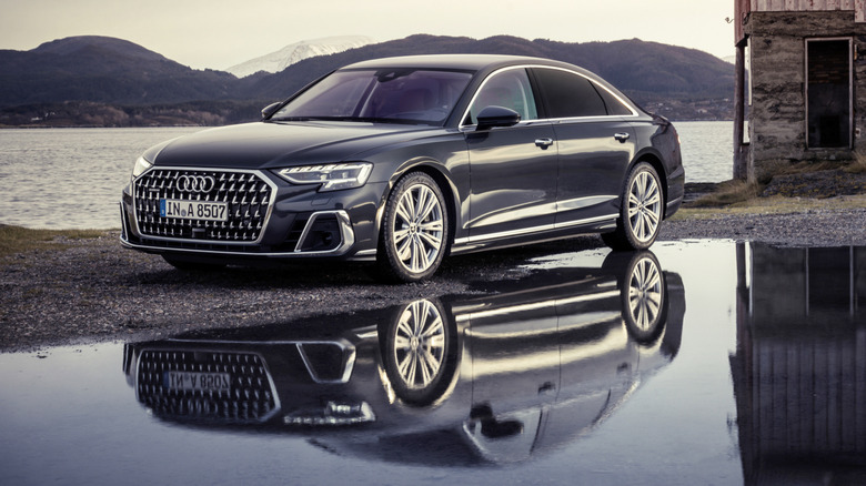 Front 3/4 view of Audi A8 reflected in water in seaside setting