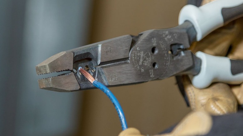 A person using Klein pliers on copper wire.