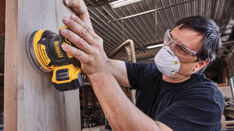 Person sanding wood surface with a DeWalt orbital sander