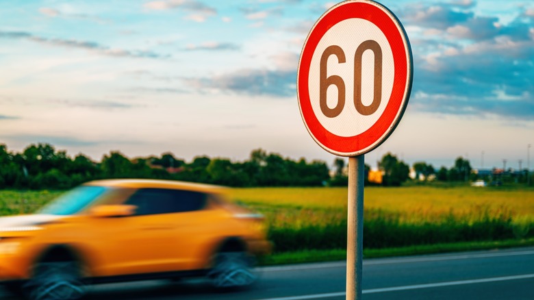 A blurred yellow car speeds past a roadside 