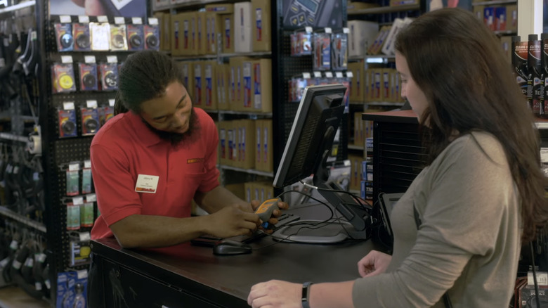 An AutoZone employee helps customer check automotive part