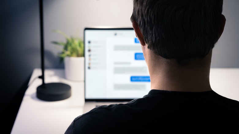 Man pictured from behind using a laptop.