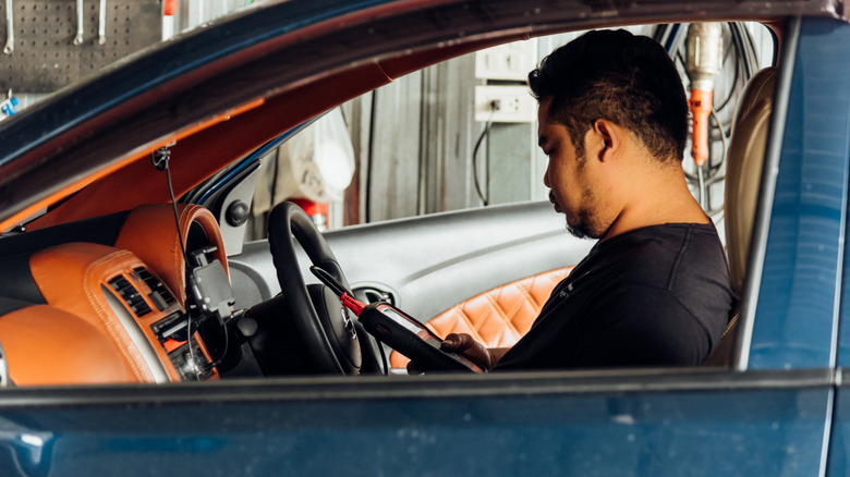 A person inside a car using an OBD-ii device to tune the car.