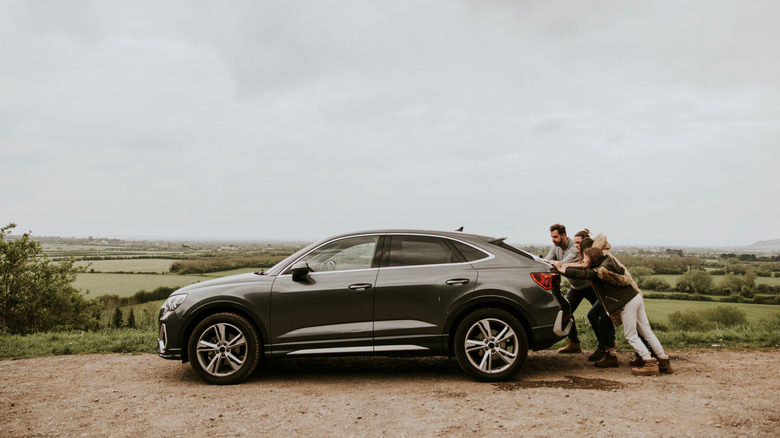 Family pushing dead car