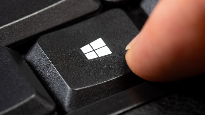 Finger pressing Windows key on keyboard, close up