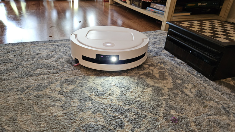 The YEEDI M14 Plus on a blue and white carpet with its light on.