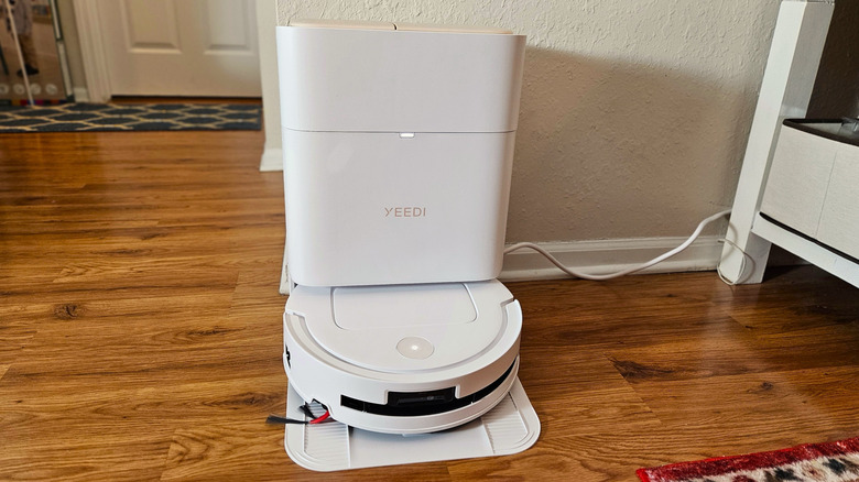 YEEDI M14 Plus robot vacuum docked in the OMNI Smart Station in white on a hardwood floor
