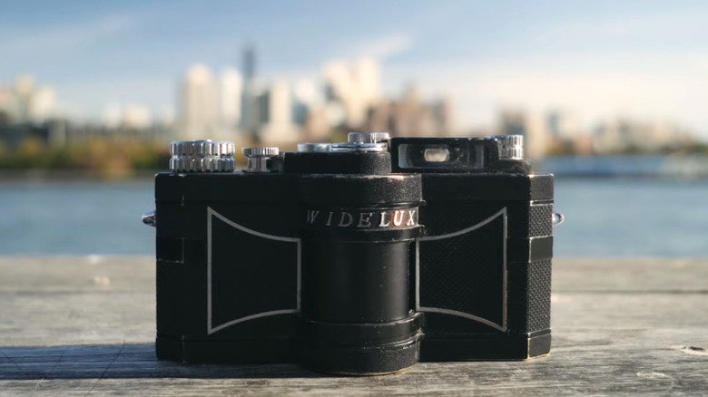 Widelux camera sitting on a deck by a river