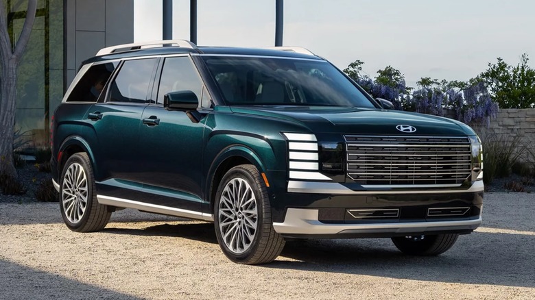 A A green 2026 Hyundai Palisade parked in front of a building.