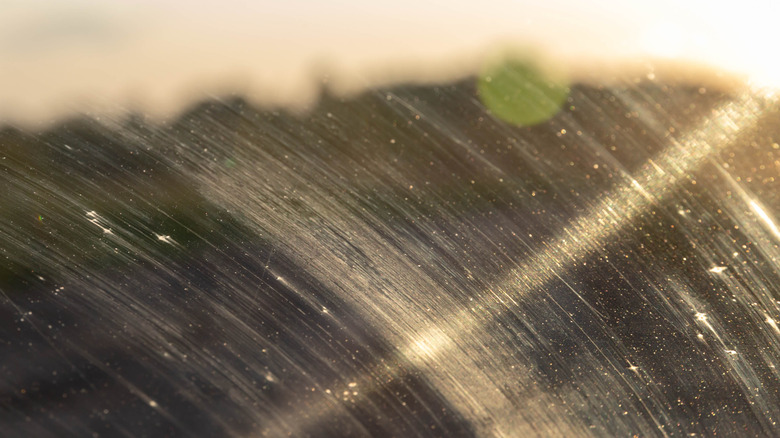 A close-up shot of a sun-soaked windshield with streaks and hard water residue
