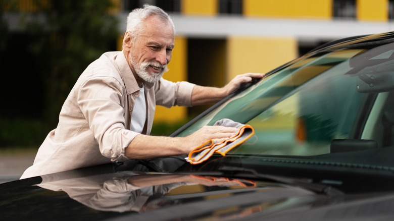 A person cleaning a car windhsield with a microfiber cloth