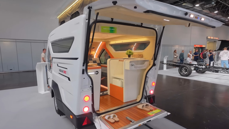 An white Aquila 360 at a car show with its rear hatch door and tailgate open