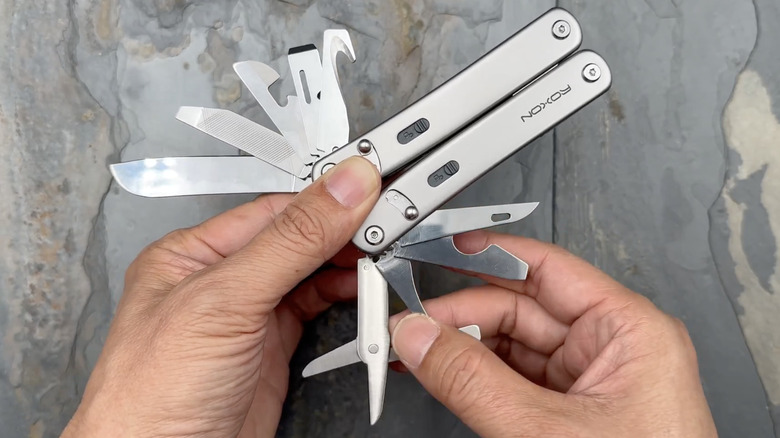 Someone holding the Roxon Flex Modular Multitool and opening several tools