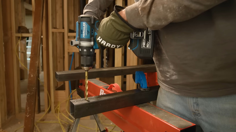 A person using the Hercules HCB91K1 cordless drill to drill holes in metal tubes