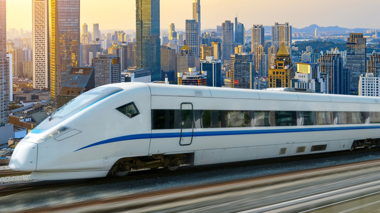 a white train speeding past a city