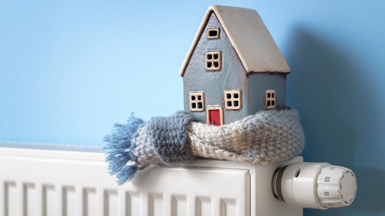 A model house wrapped in a scarf, concept of a cold home