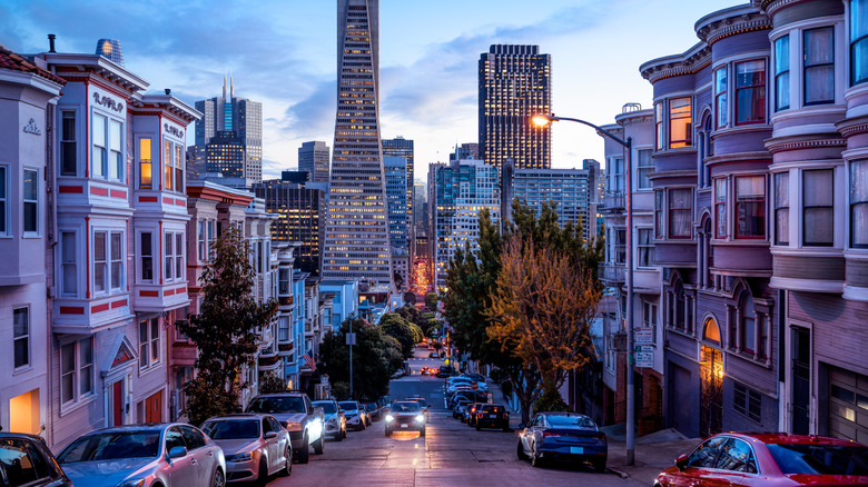 Steep San Francisco street at night with tall buildings in the background