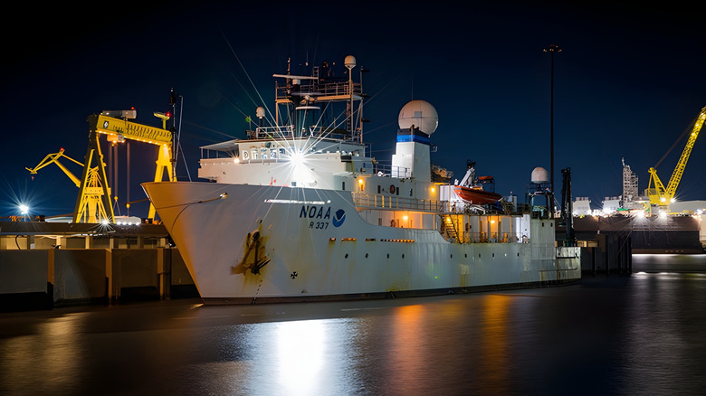 Large white ship with rusty anchor moored at shipyard at night