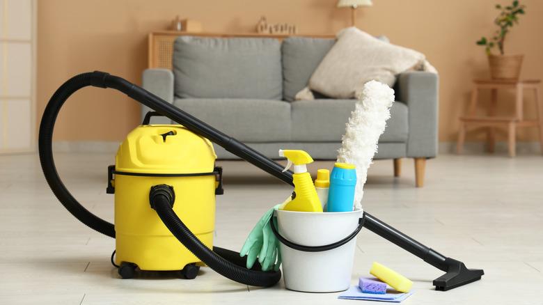 A vacuum cleaner and bucket full of cleaning supplies.