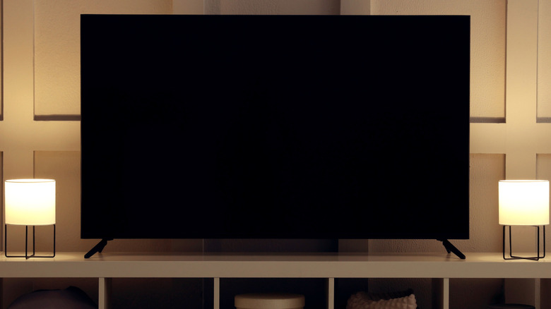 Modern TV on cabinet, armchair and lamps indoors