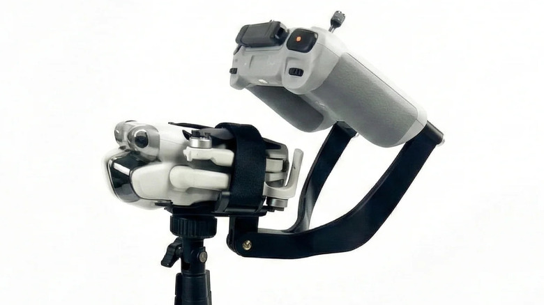 A closed up drone and controlled clamped in a black contraption mounted atop a pole.