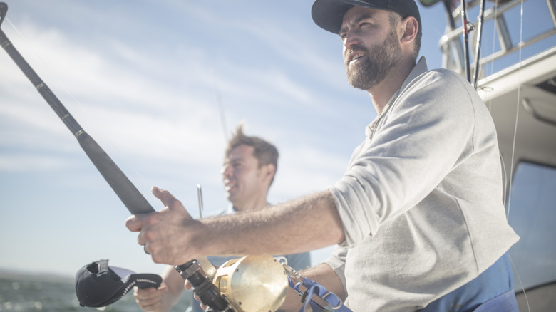 Two men deep sea fishing off a boat