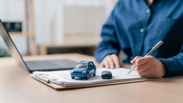 A person filling out car documents on paper.