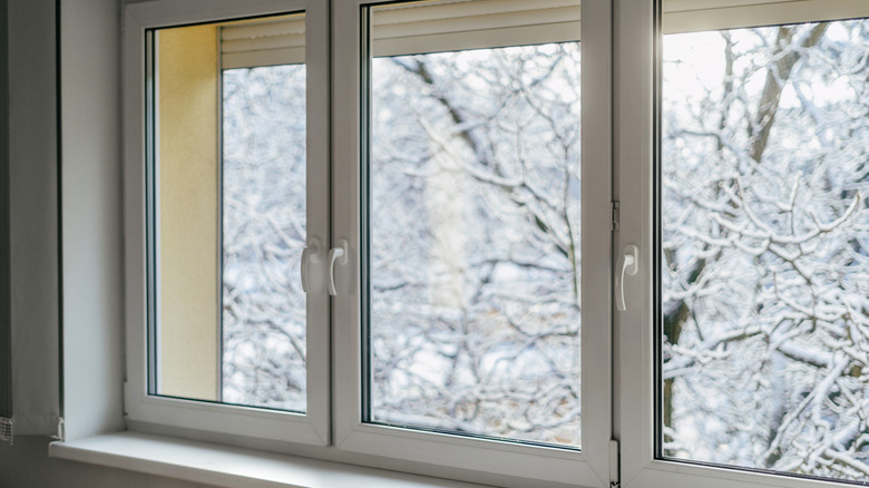 Three large white windows with snowy trees visible outside