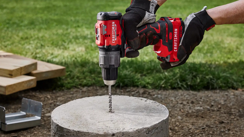 A person using a Craftsman drill on a cement pylon