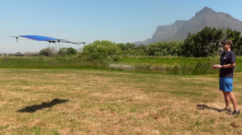 A young man piloting a solar-powered drone on a field