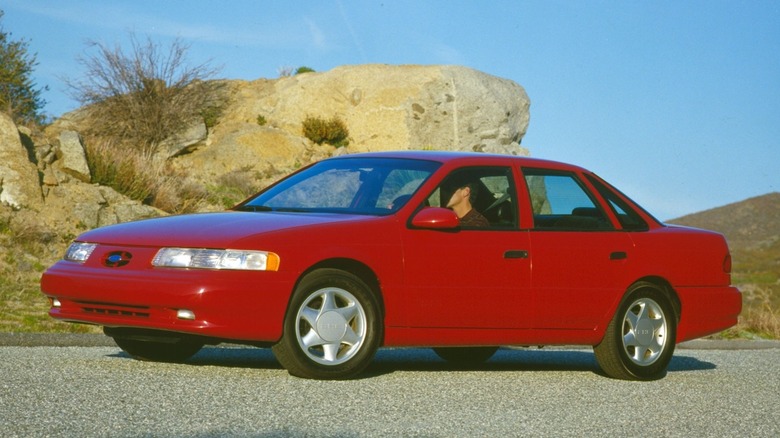 Front 3/4 view of red 1992 Ford Taurus sedan in desert setting