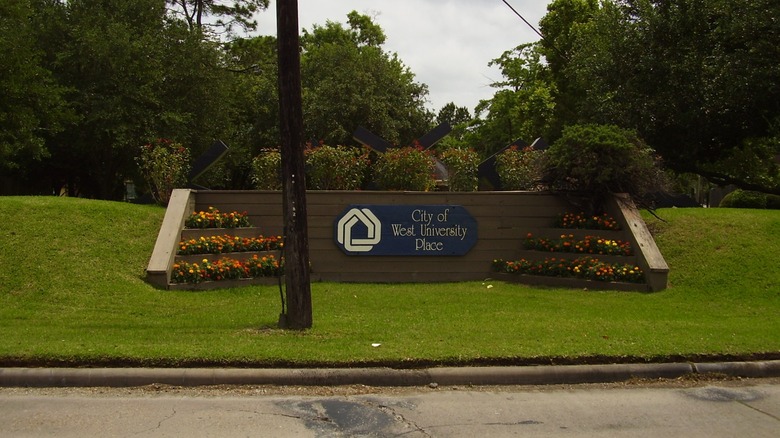 A City of West University Place sign by the roadside.
